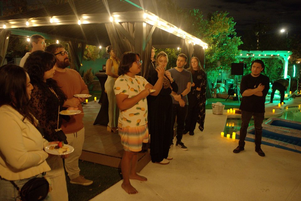Guests gathering and talking beneath string lights beside the pool