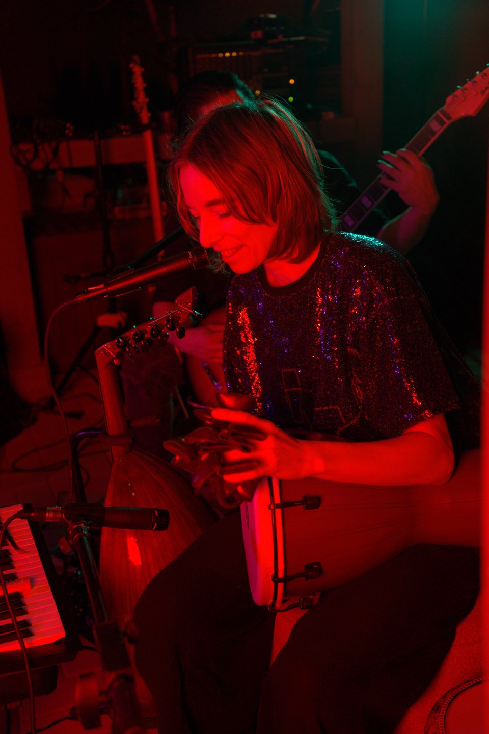 A musician playing hand percussion beside a drum and microphone
