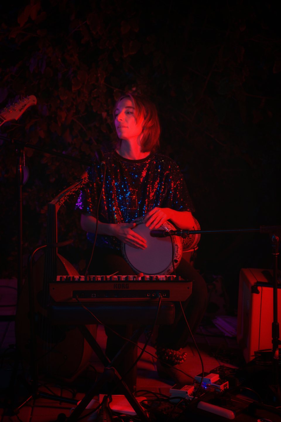 A musician performing with percussion under red stage lighting