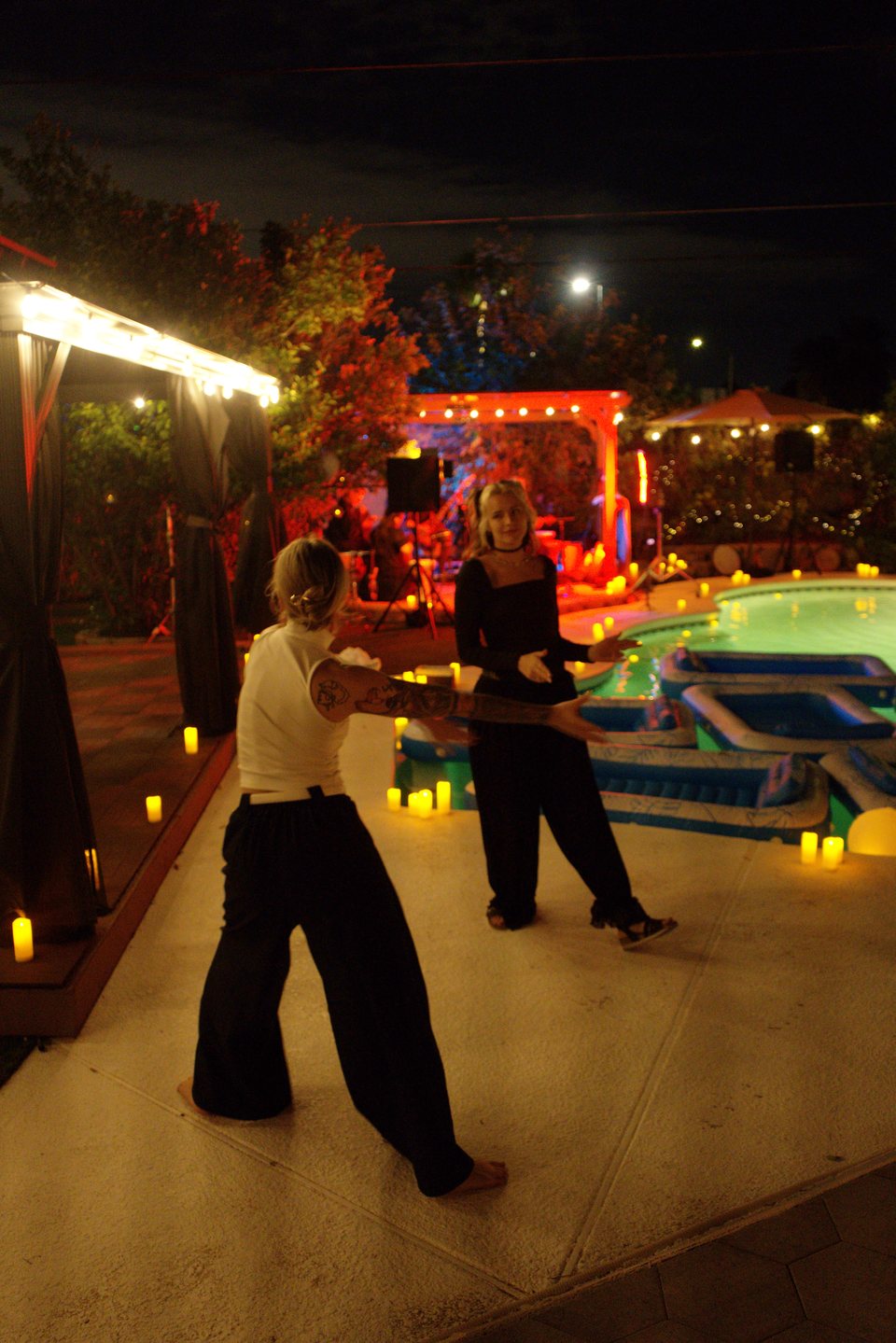 Guests beside the candlelit pool beneath string lights at the October 18 gathering